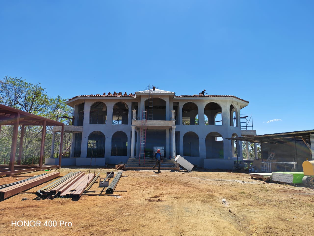 Una casa de dos pisos en construcción con arcos y trabajadores en el techo.