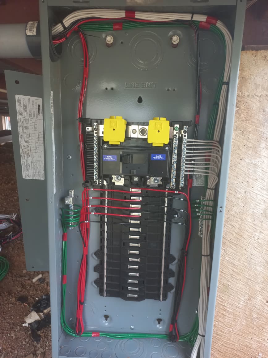 Interior de panel eléctrico Square D con cableado profesional organizado en colores rojo, blanco y verde y breakers Main Principal duales.