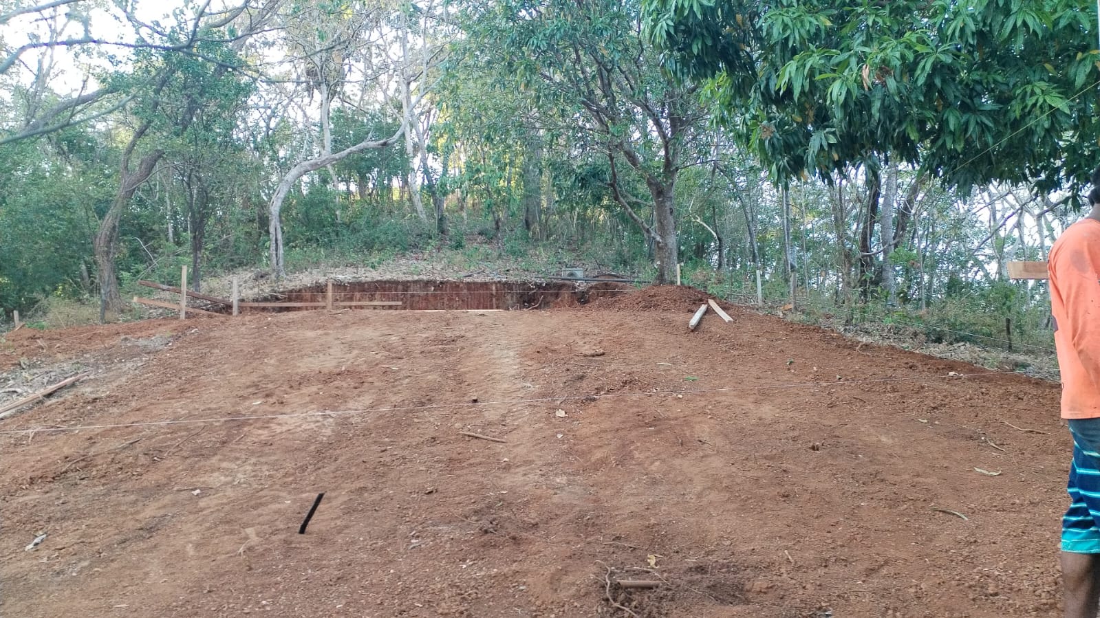 Se observa un terreno en proceso de preparación con estacas y cuerdas para una construcción.