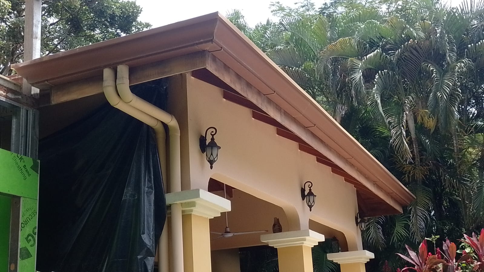 Vista exterior de una construcción con techos, canaletas y lámparas decorativas instaladas.