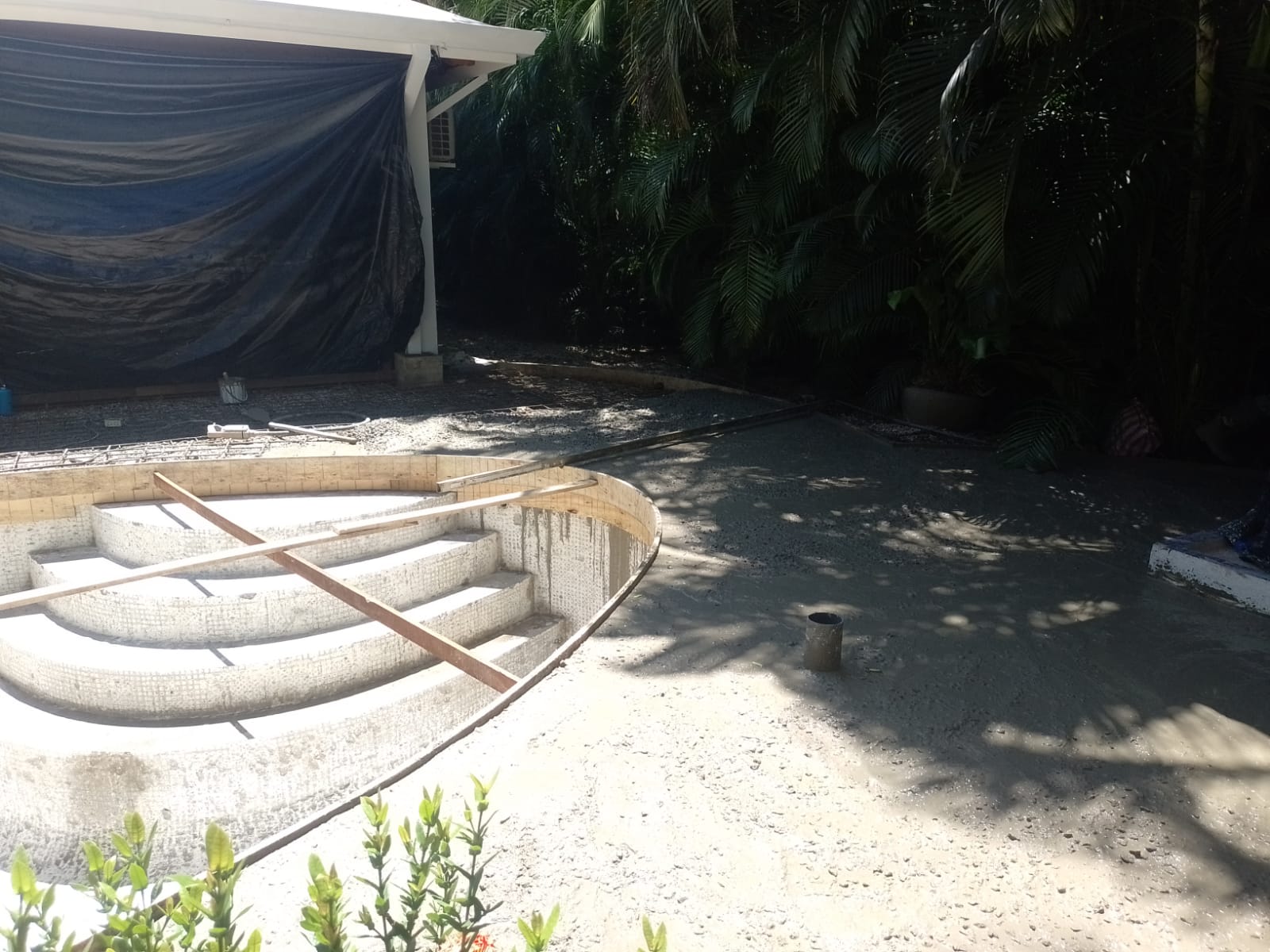 Se observa la construcción de una piscina con escalones de mosaico y el área circundante en proceso de cementado.