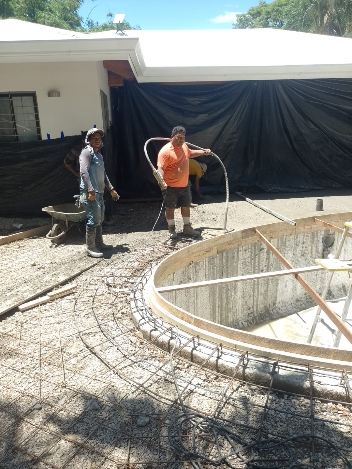 Trabajadores de construcción realizando labores de preparación para la instalación de una piscina.
